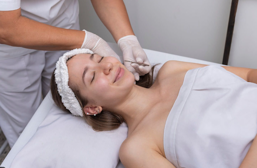 Dermaplaning facial treatment removing peach fuzz on a woman's face.