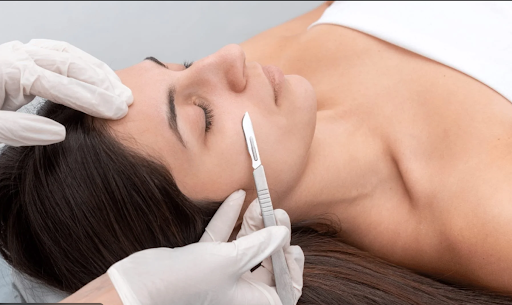 Esthetician performing a safe dermaplaning facial with a clean blade.